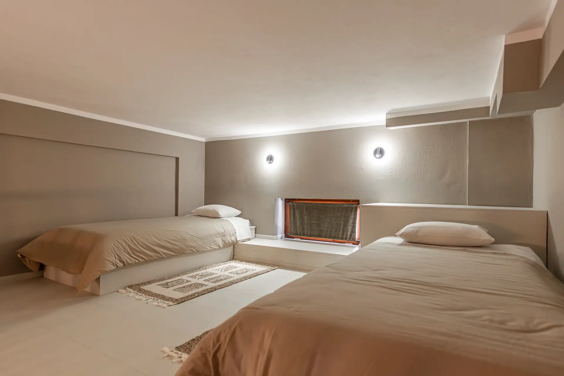 Attic loft with two single beds and beige linens