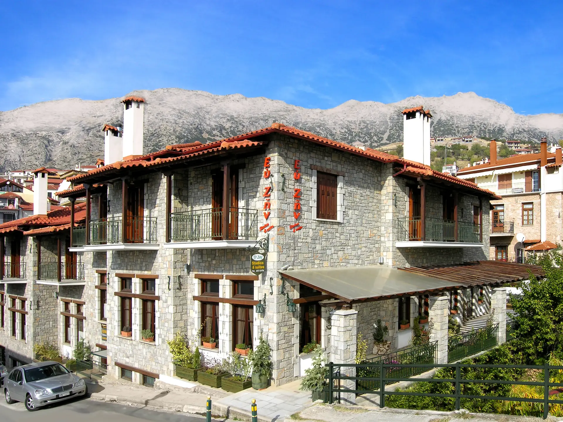 Traditional stone guesthouse with red-tiled roofs against the mountain