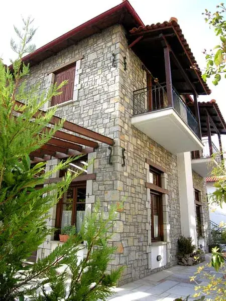 Stone hotel facade with balcony and wooden pergola
