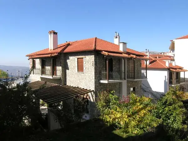 Stone hotel building with terracotta roof nestled in greenery